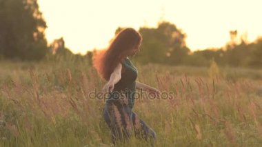 Güzel model kız kot pantolon ve güneş ışığı alan bir yeşil forması giymiş. Uzun saçlarını okşayarak ve batımını