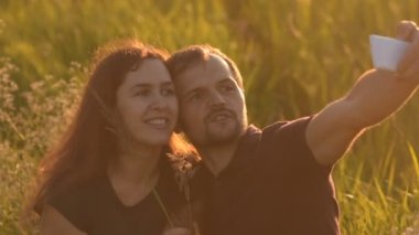Romantik Çift günbatımında parkta yürüyüş ve bir selfie yapar