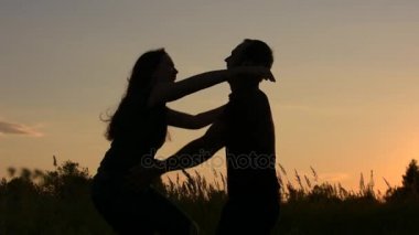 Neşeli genç kadın arkadaşı onun kollarına atlar. Günbatımı gökyüzü arka plan üzerinde.