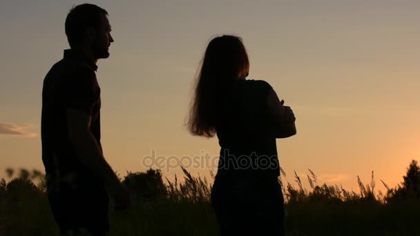 若い男は、彼の友人に返されます。彼女の肩を抱いてください。夕焼け空の背景に. — ストック動画