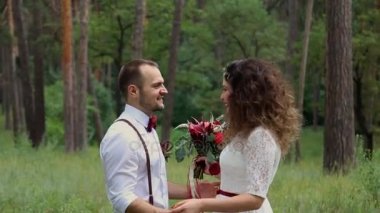 Güzel genç çift bohem tarzı moda ormanın içinde. Birbirlerinin gözlerine bakıyor. Gülümseme.