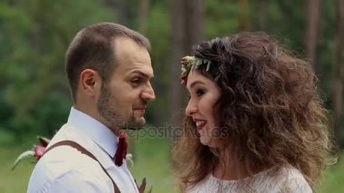 Damat ve gelin ormanda genç çift. Çalı çırpı ve çiçekleri büyük bir demet. Yakın çekim.
