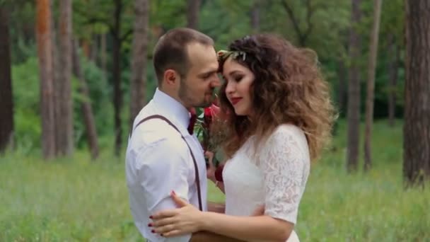 Pareja joven romántica en estilo bohemio de moda en el bosque. Mirándonos a los ojos. Sonríe . — Vídeos de Stock