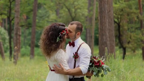 Ρομαντικό ζευγάρι γαμπρός και νύφη στο δάσος. Ένα μεγάλο μάτσο κλαδιά και λουλούδια. Χαμόγελο. — Αρχείο Βίντεο