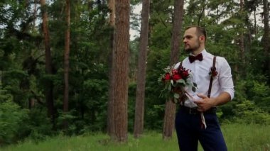 Güzel genç hippi çift kıvırcık gelin ormanda poz. Damat elinde muhteşem bir buket tutar.