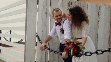 Güzel hipsters çifti Demir zinciri yaslanmış. Muhteşem bir buket tutan genç kadın. Eski ahşap çit arka plan üzerinde