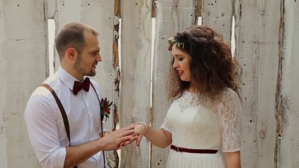 Стильный молодежный винтаж стоит рядом с белым забором. Жених взял за руку красивую невесту . — стоковое видео