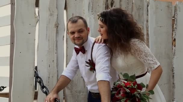 A handsome man leaned on an iron chain. Young beautiful woman hugging him. In the background of vintage white picket fence — Stock Video