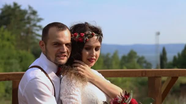 屋外でポーズ美しいカップル。新郎が花嫁、一緒に笑顔を包含します。 — ストック動画