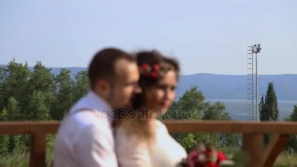 Stilvolles Paar vor dem Hintergrund von Wald und Bergen. ein junger Mann erzählt von einer schönen jungen Frau Worte der Liebe in seinem Ohr. — Stockvideo