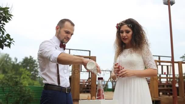 Abwechselnd gießt das Paar den Sand in die Flasche. die Sandmischung — Stockvideo