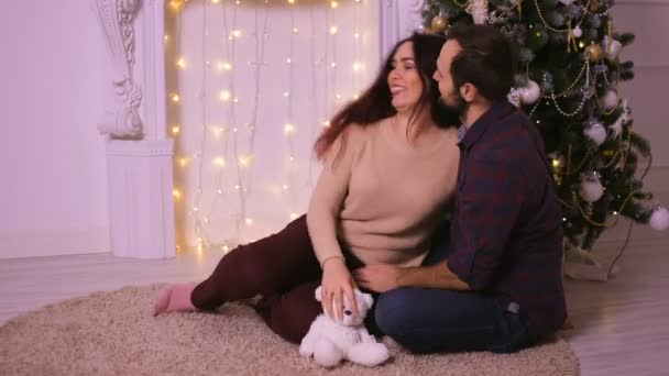 Nice love couple sitting on carpet near the fireplace. Woman and man celebrating Christmas. — Stock Video