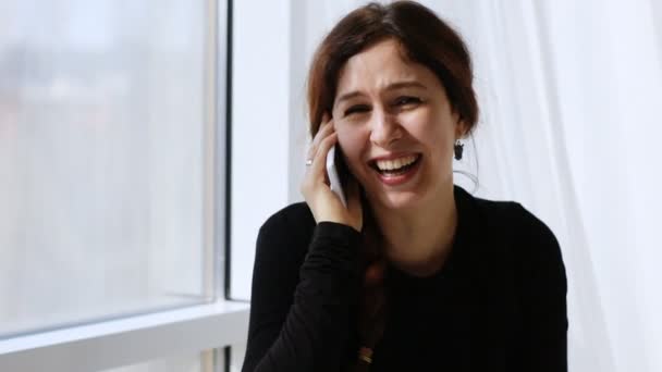 Красивая молодая женщина смеется, разговаривая по телефону — стоковое видео