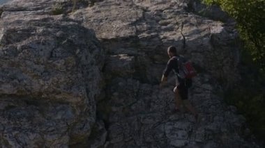 Hiking dağlarda yaz. Genç bir adam dağa tırmanıyor. Kendi korkuları ve zorluklar üzerinde zafer işareti elinde yükseltir