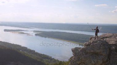 Genç adam dağın zirvesinde kendini kameraya rahatlatır.