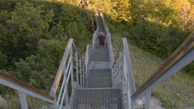 Adam sırt çantası ile dağlarda merdivenlerden tırmanıyor.
