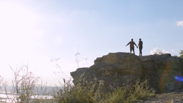 Jovens turistas com mochilas desfrutando de vista para o vale do topo da montanha. Levanta as minhas mãos. — Vídeo de Stock