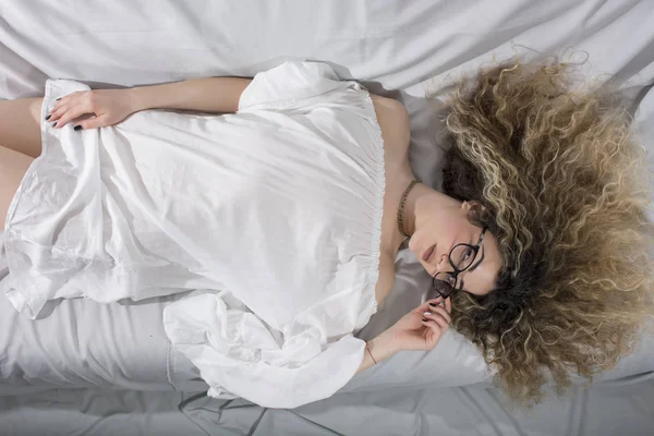 Donna Con Capelli Ricci Abito Bianco Posa Sul Letto — Foto Stock