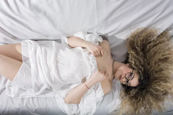 Жінка Кучерявим Волоссям Біла Сукня Позує Ліжку — стокове фото