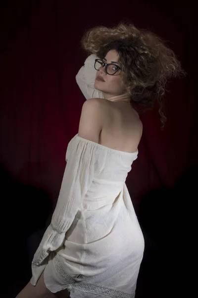 巻き毛とポーズを黒と赤の背景に白いドレスの女性 — ストック写真