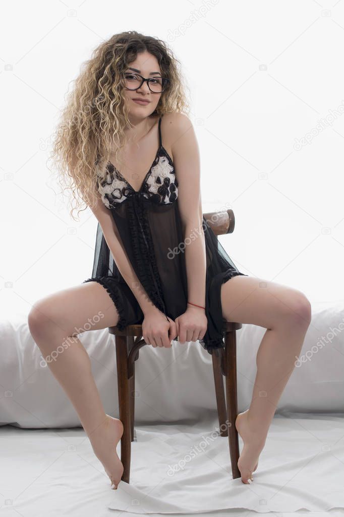 Woman with curly hair dressed in black babydoll posing on white background