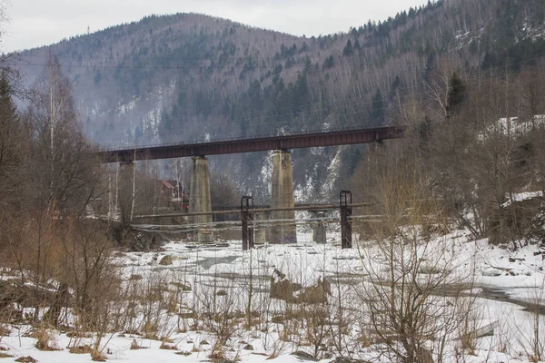 Old abandoned railway bridge on a background of mountains in the Carpathian village of Yaremche in winter. Ukraine
