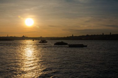İstanbul Boğazı 'ndaki bir teknenin silueti gün batımında İstanbul' un arka planında. Türkiye