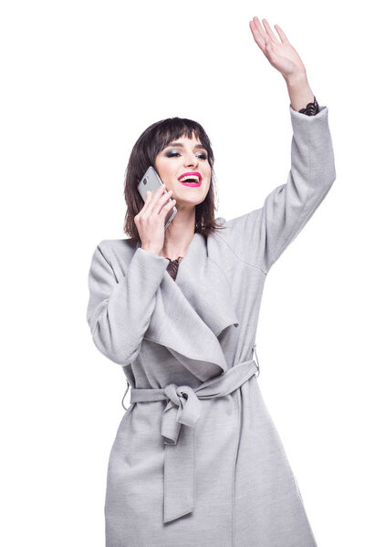 Beautiful woman dressed in a gray coat waving talking on the phone