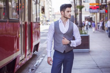 Genç yakışıklı işadamı akıllıca, şehrin içinden yürüyüş giyinmiş