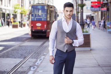 Genç yakışıklı işadamı akıllıca, şehrin içinden yürüyüş giyinmiş