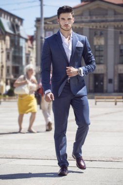 Genç yakışıklı işadamı akıllıca, şehrin içinden yürüyüş giyinmiş