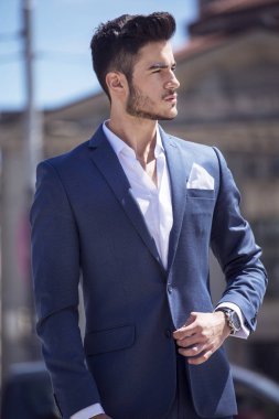 Genç yakışıklı işadamı akıllıca, şehrin içinden yürüyüş giyinmiş
