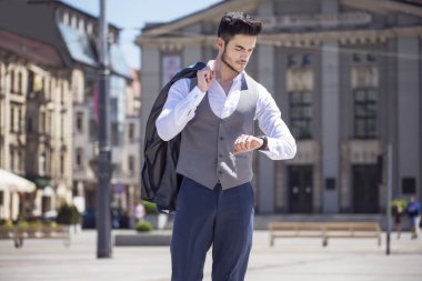 Yakışıklı genç zarif şehirde yürürken saatine bakarak giyinmiş