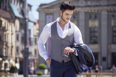 Yakışıklı genç zarif şehirde yürürken saatine bakarak giyinmiş