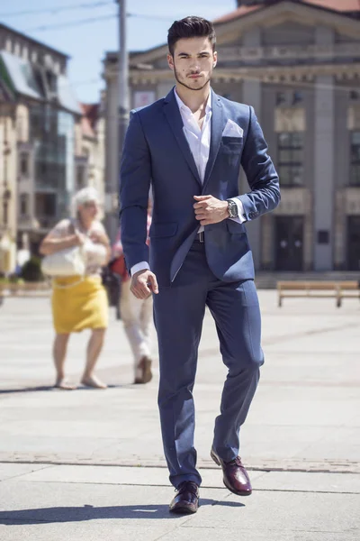Genç yakışıklı işadamı akıllıca, şehrin içinden yürüyüş giyinmiş