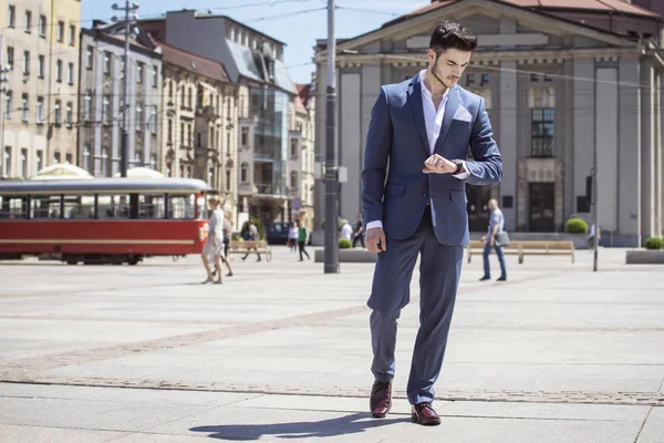 Yakışıklı genç zarif şehirde yürürken saatine bakarak giyinmiş
