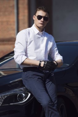  Yakışıklı delikanlı, bir şehir bina arka plan üzerinde siyah bir araba duruyor