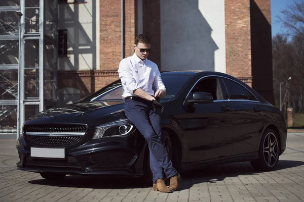  Yakışıklı delikanlı, bir şehir bina arka plan üzerinde siyah bir araba duruyor