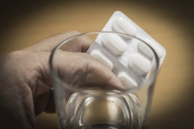 Tabletler ve bir bardak su ile el