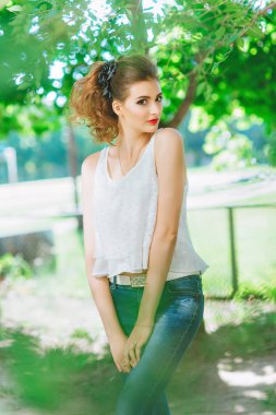 genç kadın açık havada beyaz bir t-shirt ve jeans, parlak makyaj, kırmızı dudaklı. Kameraya bakarak