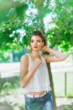 genç kadın açık havada beyaz bir t-shirt ve jeans, parlak makyaj, kırmızı dudaklar