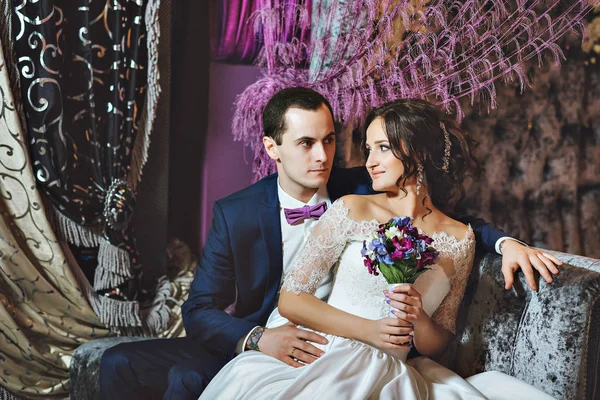 Hochzeitstag. Braut und Bräutigam in einem luxuriösen Interieur in Lavendelfarbe. Hochzeitsgefühle. schöne Braut und eleganter Bräutigam bei der Zeremonie. — Stockfoto