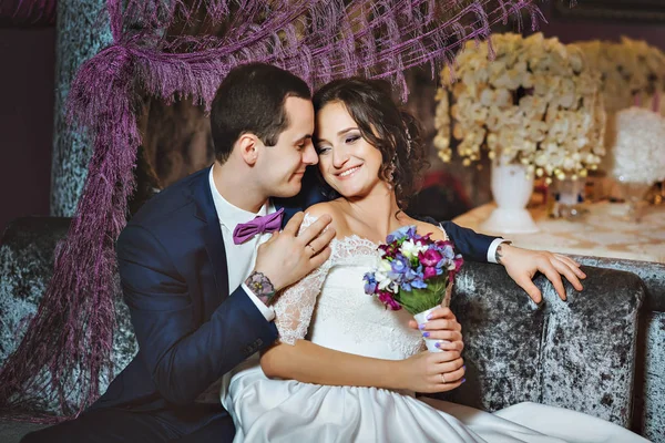 Hochzeitstag. Braut und Bräutigam in einem luxuriösen Interieur in Lavendelfarbe. Hochzeitsgefühle. schöne Braut und eleganter Bräutigam bei der Zeremonie. — Stockfoto