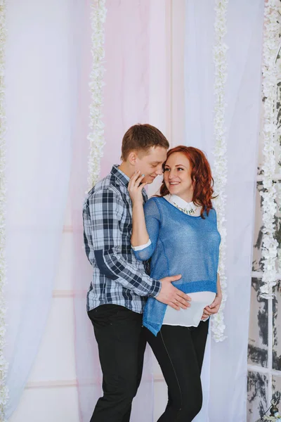 Portrét veselé těhotné ženy s baby kostky na její břicho a její manžel ji políbil na pohovce — Stock fotografie