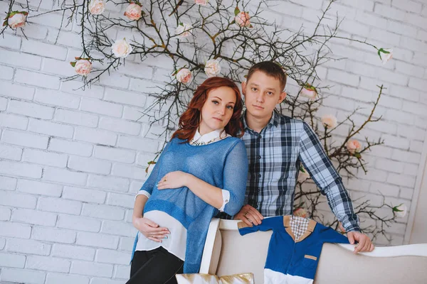 Una joven pareja embarazada enamorada de pie cerca. El marido abraza a su esposa. Con colores de cuarzo rosa y azul cielo . — Foto de Stock