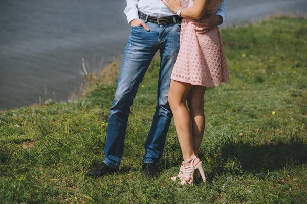 Benen voeten verliefde. Staande arm in arm op het groene gras in de buurt van de zee. — Stockfoto