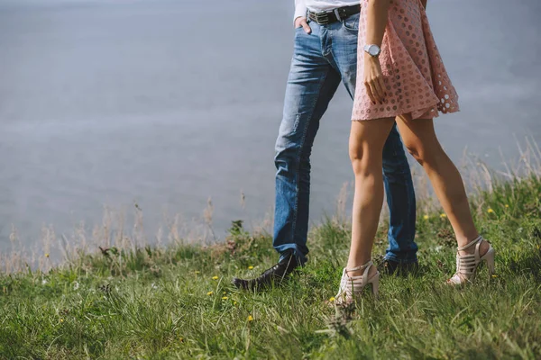 Pieds jambes couple amoureux. Marcher sur l'herbe verte près de la mer . — Photo