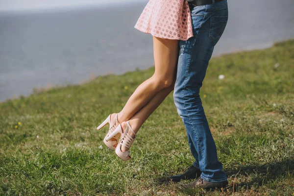 Benen voeten verliefde. Hij draait haar in zijn armen, op het gras in de buurt van de zee. — Stockfoto