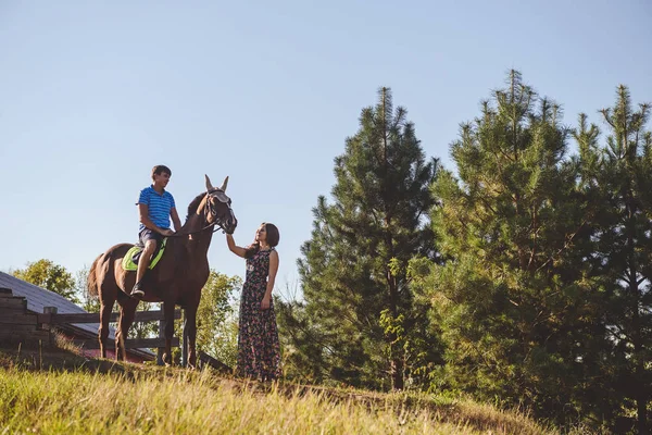 Romantic young couple in love, walk on horseback, on nature background. A woman touches the hand of a horse. Concept: love, romance, Hobbies