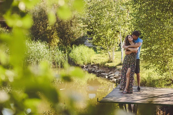 Boldog romantikus pár fahíd a tónál. Ember átfogja, és megcsókolja a fiatal nő. — Stock Fotó